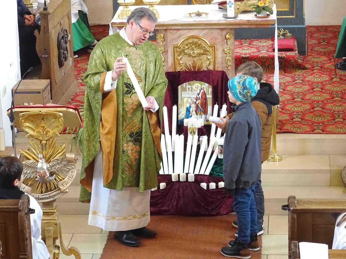 Pfarrer Kohler mit den Kommunionkindern und ihren Kerzen.