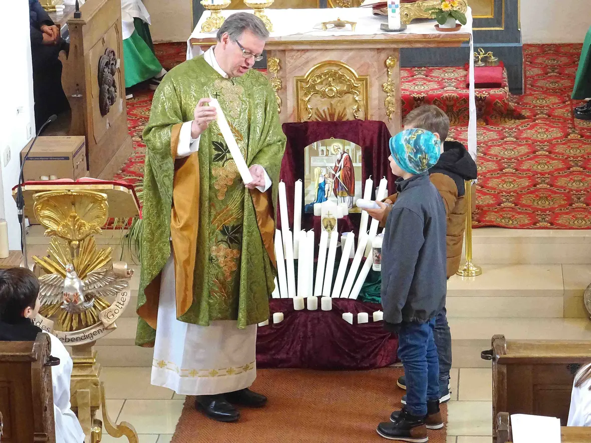 Sonntagsgottesdienst St. Martin Pfarrer Kohler mit den Kommunionkindern und ihren Kerzen.