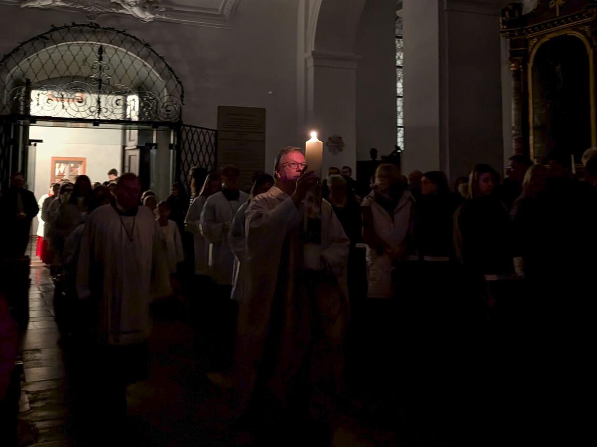 Stadtpfarrer Herbert Kohler trägt mit der Osterkerze das Licht in die Kirche ...