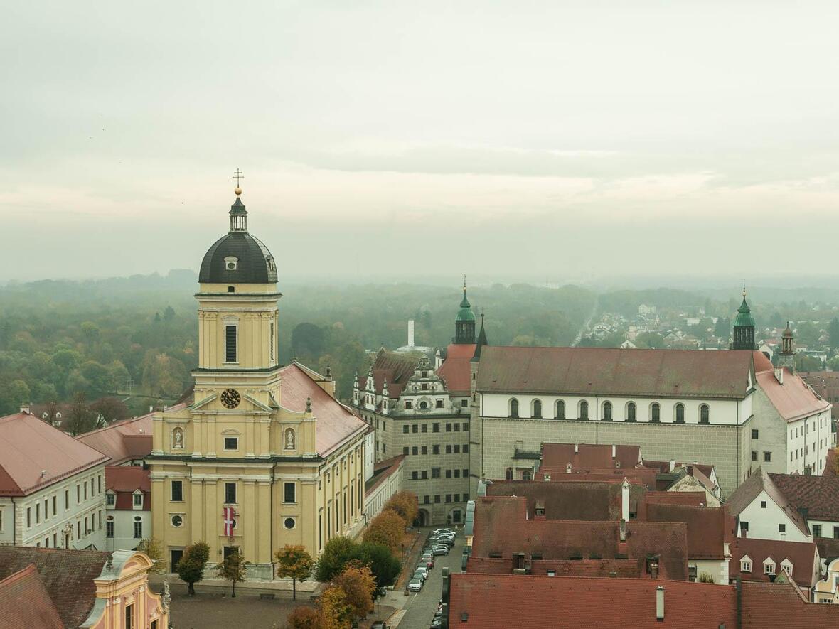 Genießen Sie den Blick auf die Hofkirche mit Kirchweihfahne und das Neuburger Schloss