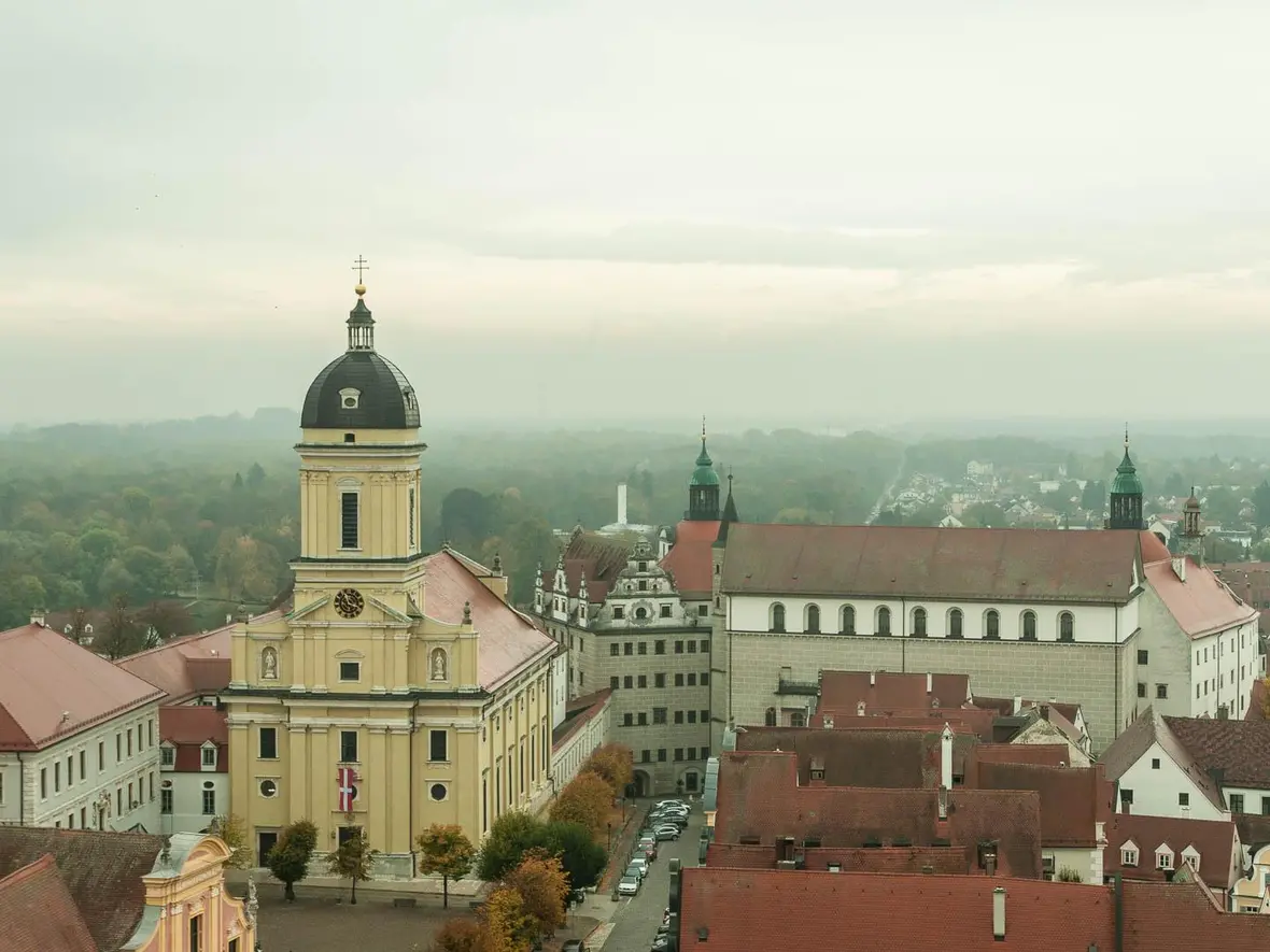 Genießen Sie den Blick auf die Hofkirche mit Kirchweihfahne und das Neuburger Schloss